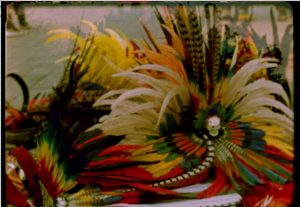 A multiple exposure film still featuring brightly colored feathers. 