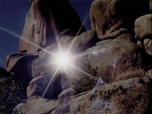 An outcropping of rocks with a bright light shining from them.
